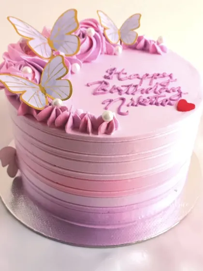 A pretty ombre cake in shades of pink and purple, adorned with delicate butterflies.