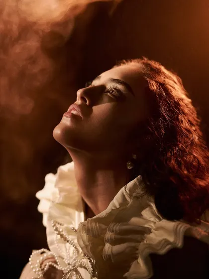A beauty shot with a fine art feel. We used a hazer to create a soft, smoky atmosphere, and a single, hard light source to sculpt the model's face and create this dramatic, painterly look.