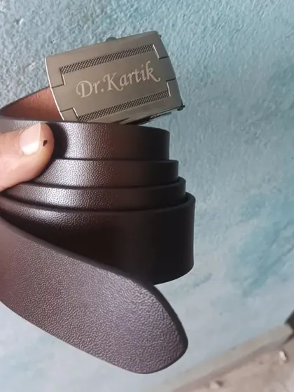This personalized leather belt has the name and title 'Dr. Kartik' engraved directly onto the buckle, making it a unique and professional accessory.
