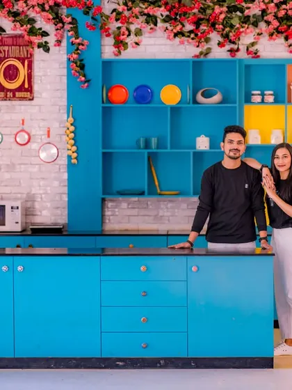 A stylish portrait in a colorful kitchen set. The couple's coordinated casual outfits look great against the bright, modern backdrop.