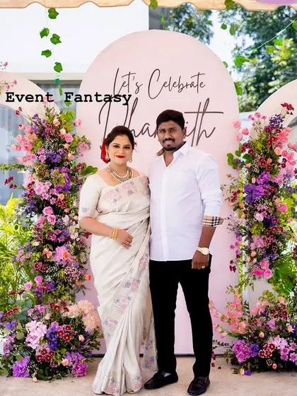 A lovely photo of the couple at Dhanvith's celebration, surrounded by stunning floral arches.