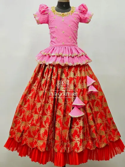 A grand Banarasi lehenga in red and pink. The pink peplum top is paired with a red brocade skirt with multiple layers and ruffles.