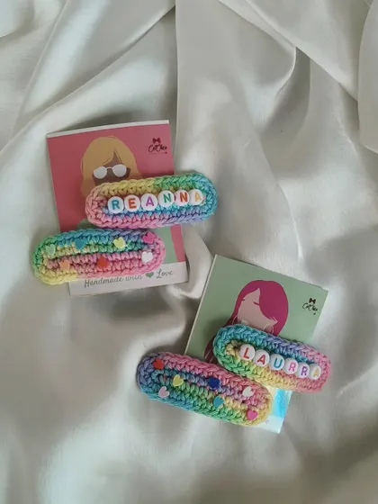 A pair of our custom name clips for Reanna and Laura, showcasing the pretty pastel rainbow yarn we use.