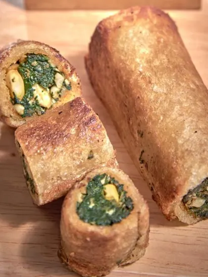 A cross-section of our savory spinach and corn roulade, showcasing the delicious filling inside a crispy, golden-brown exterior.