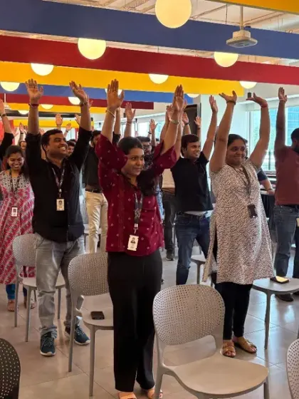 A moment of collective energy as employees stretch their arms overhead, a simple yet powerful move to awaken the body and mind.
