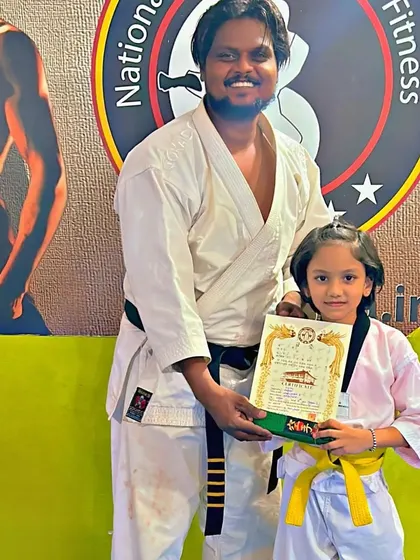 A young girl is all smiles as she receives her green belt certificate in Taekwondo.