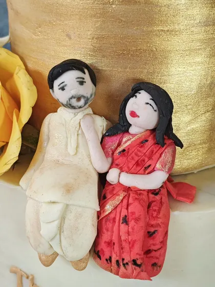 This detailed shot shows the delicate painting and sculpting on the fondant couple topper. From the groom's beard to the bride's expression, every element is carefully considered.