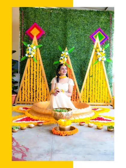 A beautiful portrait of the bride at her Haldi ceremony, surrounded by a vibrant setup of yellow and orange marigolds.