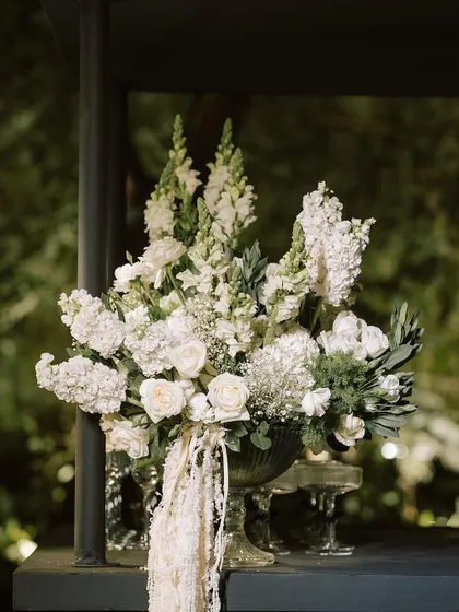 A beautiful centerpiece of white roses, snapdragons, and baby's breath in a classic glass vase, perfect for an elegant evening affair.