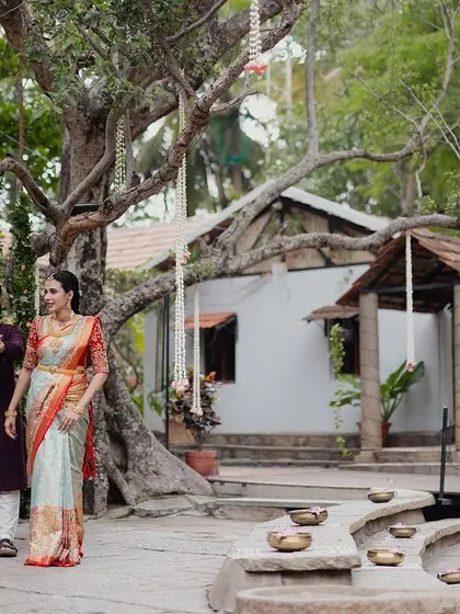A couple walks through the courtyard, framed by ancient trees and a decorated swing, a perfect wide shot to capture the scale and beauty of the property.