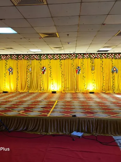 A simple Haldi stage with a full yellow drape backdrop. The stage is kept clean and open, ready for the fun and messy Haldi rituals.