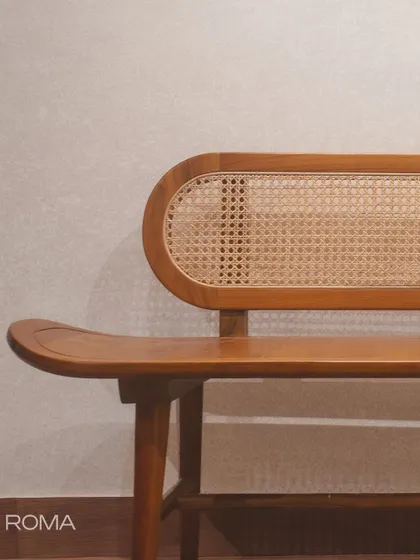 The 'Roma' bench, with its distinctive pill-shaped rattan backrest and gracefully curved seat. It's a masterpiece of craftsmanship.