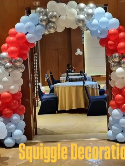 A red, white, and blue balloon arch for a 'Cars' themed birthday party, complete with a personalized welcome sign.