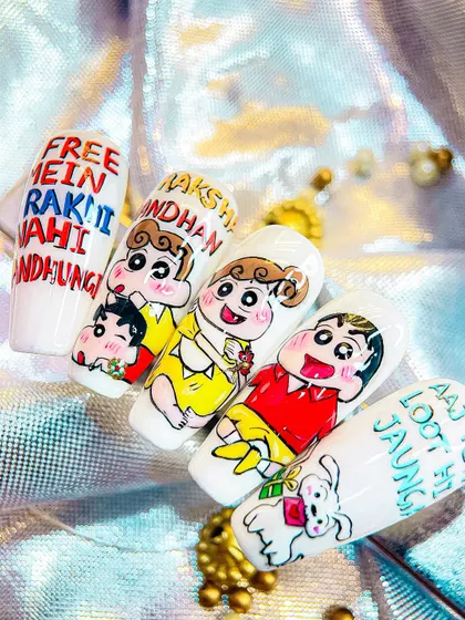 A close-up of the Shinchan Rakhi nails, showing the detailed character art and the humorous text "Free mein rakhi nahi bandhungi".