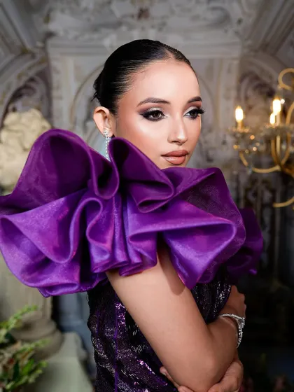 The entire look is about drama and elegance, from the ruffled sleeves to the sharp, clean makeup.