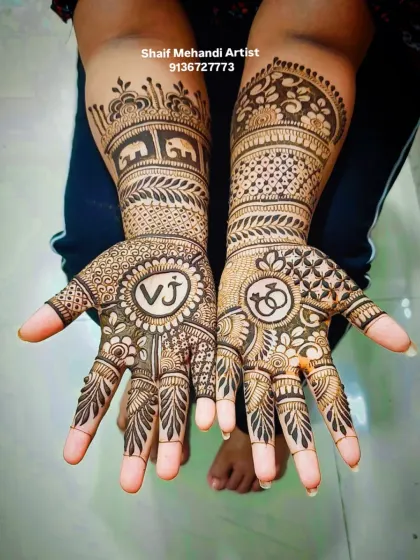 A clear shot of the engagement mehandi with 'VJ' initials, interlocking rings, and elephant motifs.
