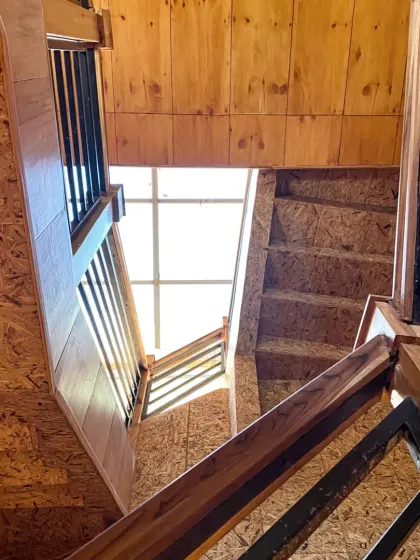 A view looking up the stairwell towards a skylight, emphasizing the verticality of the space and how we use natural light as a core design element.