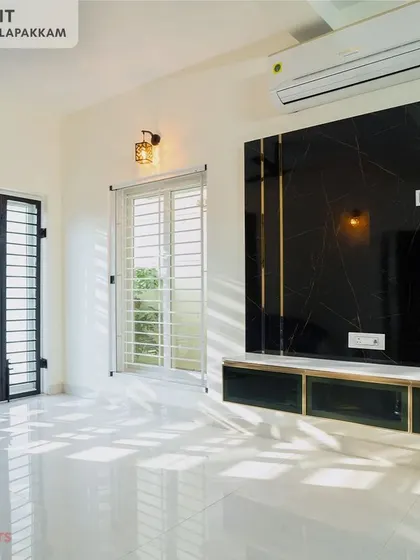 A sleek, wall-mounted TV unit in a bedroom at the Sithalapakkam villa, featuring a black marble-finish panel with golden inlays for a touch of luxury.