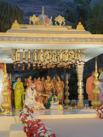 A classic South Indian temple-style mandap set against the beautiful backdrop of Della Resorts. The intricate gold pillars and traditional floral hangings create a sacred and timeless space for the wedding rituals.