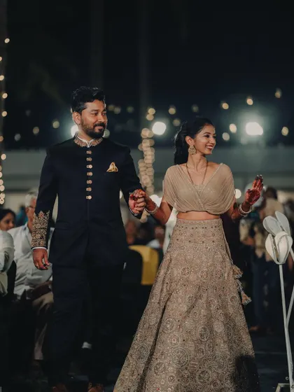 The couple walking hand-in-hand through their beautifully lit reception venue.