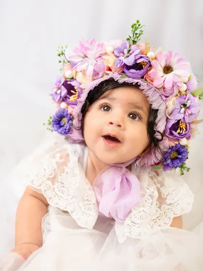 A look of pure wonder from an eight-month-old in a stunning purple and pink floral bonnet. The details in this accessory are just magical.