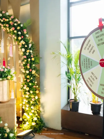 A badminton court is transformed into a beautiful Mehendi venue, with a fun "spin the wheel" game ready for guests.
