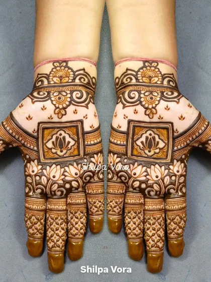 A symmetrical design with a central lotus in a square frame, surrounded by delicate floral patterns.