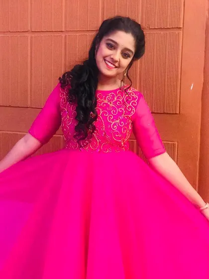 The joy on her face says it all! This shot captures the beautiful fit and flare of the custom pink gown, designed to be comfortable yet stunning under the studio lights for her TV appearance.