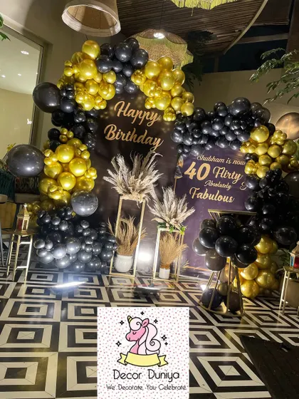 Here’s a look at a chic and modern 40th birthday celebration we designed. The decor features a bold black and gold balloon arch, a custom backdrop, and elegant pampas grass arrangements for a sophisticated party vibe.