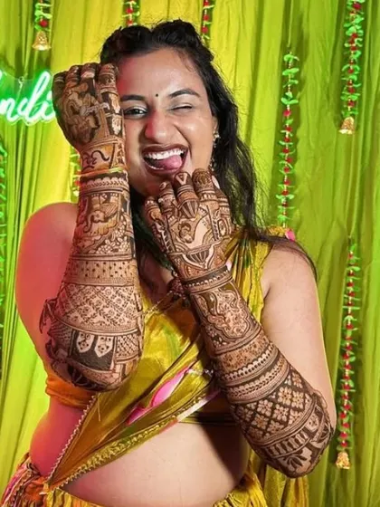 The pure joy of a bride with her wedding mehendi. This design is packed with traditional elements that cover her arms completely.