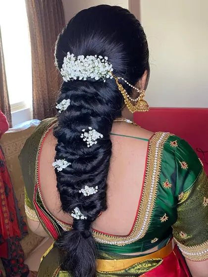 A messy braid for an engagement bride, styled with a jasmine gajra and sprigs of baby's breath for a fresh and celebratory feel.