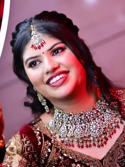 A happy bride wearing a grand moissanite choker with ruby-colored drops, a perfect statement piece for a velvet reception outfit.