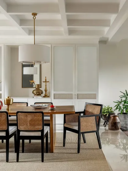 Classic and sophisticated, this dining room features a coffered ceiling and elegant cane-back chairs. The built-in cabinetry with mirrored panels adds depth and a touch of glamour.