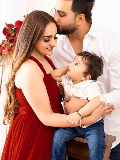 A beautiful family portrait filled with love and affection. The father's kiss on the mother's forehead adds a touch of romance and tenderness.