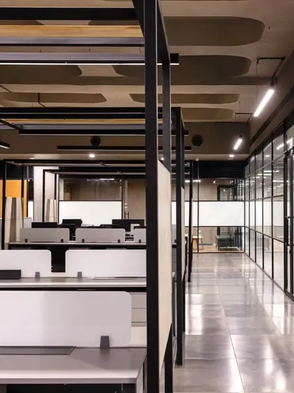 The open-plan workstation area at Anthea Pharma, designed to blend industrial aesthetics with modern functionality. Private cabins line the periphery, offering a balance between collaborative open spaces and secluded areas for focused work.