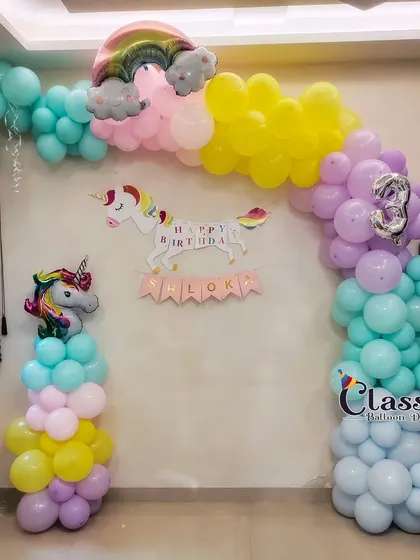 A magical Unicorn themed balloon arch in pastel rainbow colors with unicorn cutouts and foil balloons.