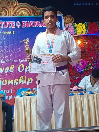 A purple belt student proudly displays his trophy and certificate after a win at a state-level open championship. Belt grading and competitions keep our students motivated.