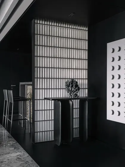 The entrance console and bar area in the Vaulted Haus are separated by a vertical partition of frosted solid glass bricks. The material's ability to refract light creates a soft glow, dividing the space while maintaining a visual connection.
