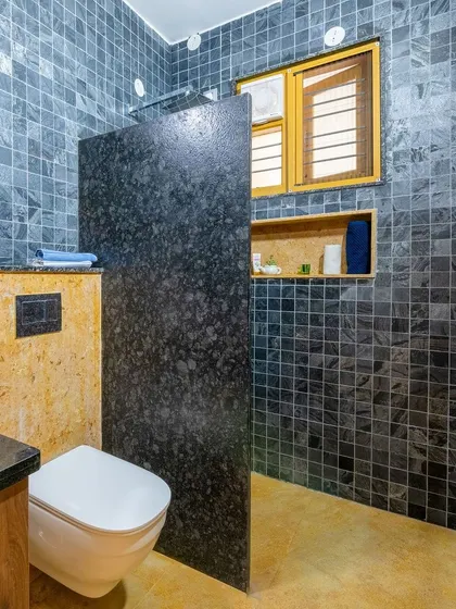 The material palette in this bathroom is a bold mix of black slate, yellow sandstone, and dark granite.