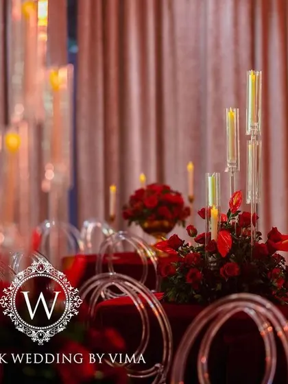 A luxurious centerpiece featuring a bouquet of deep red roses in a golden vase. This classic and elegant detail was part of a glamorous red-themed reception.