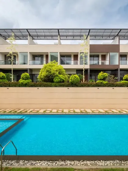 The linear design of the pool is complemented by the soft textures of the surrounding landscape. Paving stones with grass joints and structured green pockets break up the hardscape, creating a harmonious rhythm that connects the built form with the natural environment.