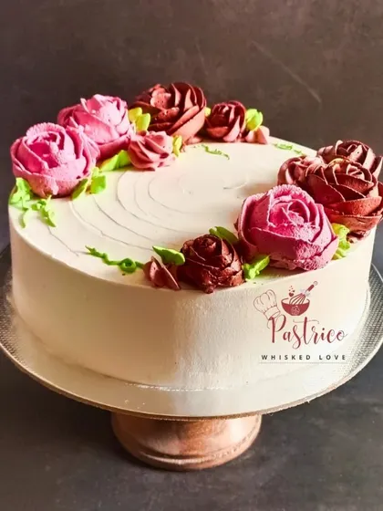 An elegant floral wreath cake with coffee-caramel flavour, featuring hand-piped roses in shades of pink and deep red.