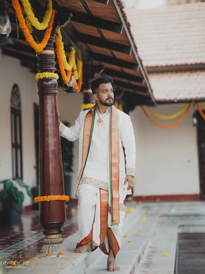 A full shot of the groom's attire, showing how a single piece of traditional jewellery can complete the wedding look with a touch of heritage.