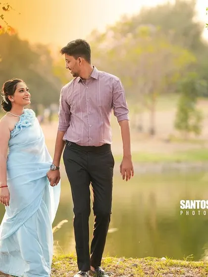 A beautiful, sun-kissed photo of a couple walking hand-in-hand by a lake.
