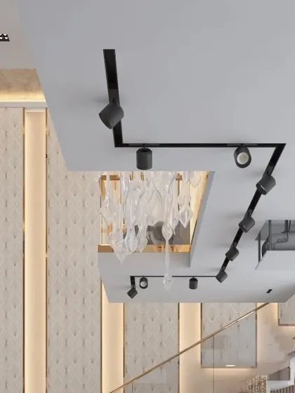 A detail of the complex ceiling design, which combines different levels, track lighting, and a modern chandelier to create visual interest and define different zones within the open space.