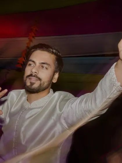 The groom shows off the bride's name written on his hand, a fun detail from the Sangeet night.