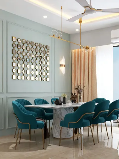 An opulent dining room featuring plush teal velvet chairs, a marble-topped table, and a stunning mirrored wall art piece. The space feels both grand and inviting.