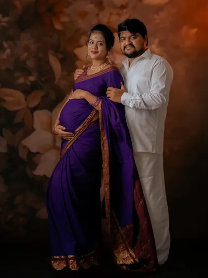 A lovely couple portrait celebrating their pregnancy journey. The rich purple saree and traditional white attire create a beautiful contrast.