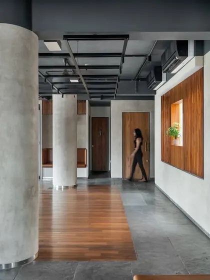 Our material strategy for this space involved a dialogue between textures. Honed Chiku limestone flooring provides a neutral base, while lime-plastered walls add warmth, and the exposed dark grey ceiling with its functional grid adds an industrial character.