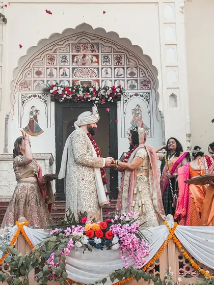 The couple holds hands after exchanging garlands at their beautiful outdoor destination wedding.